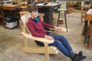 junger Kursteilnehmer sitzt auf seinem selbst hergestellten Adirondack chair probe