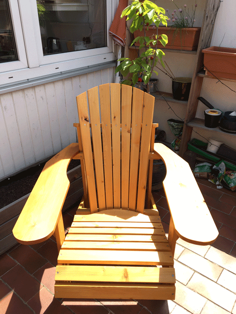 In der Sonne steht der farblos, mit Wetterschutz-Öl behandelte Adirondack chair auf dem heimischen Balkon.